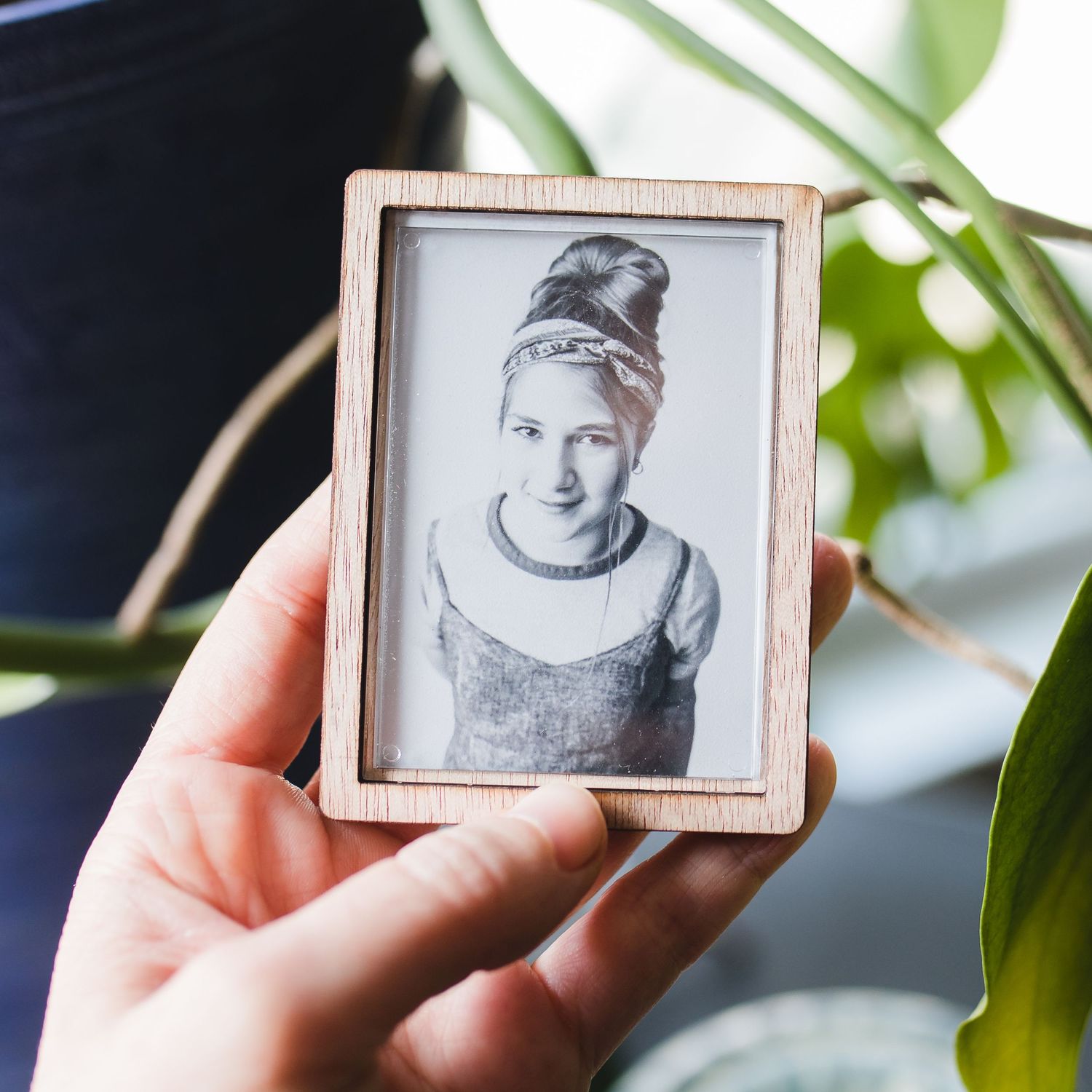 Hand holding small framed black and white portrait photograph.