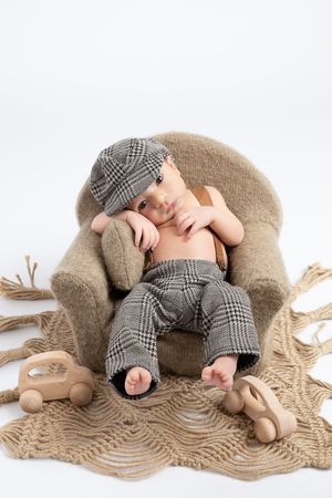 A cozy scene with brown knit blanket, wooden toys, and plaid clothing set against a white background.