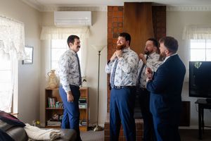 groomsmen in matching blue pants and patterned dress shirts getting ready before the ceremony Candid wedding photography Kirsten Graham