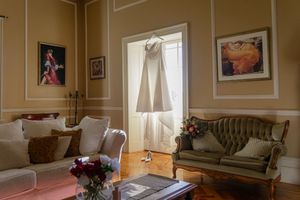 brides dress hanging from the window in a cozy living room interior features traditional decor, moldings, and natural light.