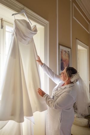 Bride admiring her wedding dress, before the ceremony in a bright interior room.