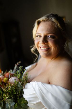 Close up profile shot of bride in a white strapless dress with delicate floral arrangements in soft focus.