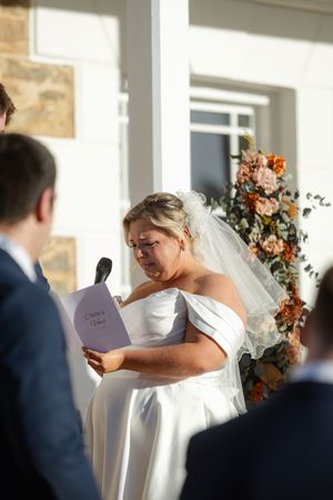 Emotional wedding ceremony moment with couple exchanging vows under floral arch decorations.