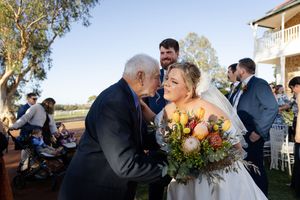 Outdoor wedding celebration with guests congratulating the bride and groom