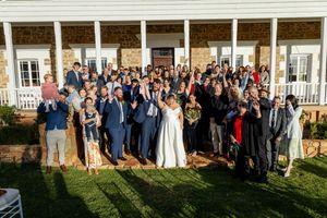 Large group wedding photo taken outside a grand white building with all guests and wedding party.