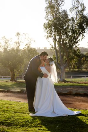Romantic sunset wedding photos of couple embracing on grassy field with golden sunlight. Buckland Estate wedding