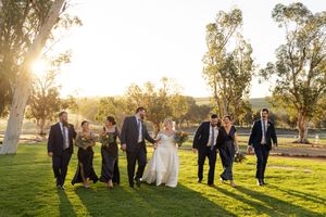 Wedding party walks together during golden hour sunset in rustic outdoor setting among trees. Buckland Estate Kirsten Graham wedding