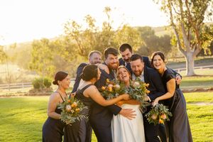 Wedding party celebrating with sunflowers and navy dresses on sunny lawn.