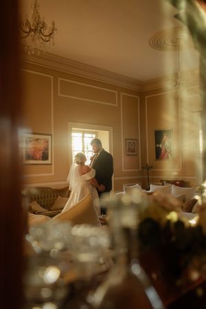 Intimate indoor wedding ceremony with soft window lighting and decorative table settings.