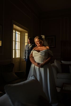 Dramatic silhouette of couple embracing in elegant room with window light.