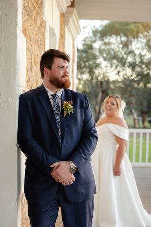 Elegant wedding portrait against stone wall with autumn floral boutonniere.
