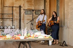 Musicians perform with string instruments in an elegant wood-paneled venue during a formal celebration.