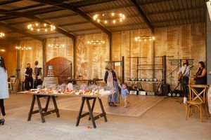 Large rustic indoor wedding venue with wooden beams and string lights creating a romantic atmosphere.