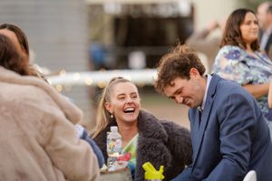 Wedding guests enjoying a casual outdoor reception with laughter and conversations.
