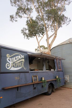 Vintage blue food truck with 'Sultan Pepper' signage parked under eucalyptus trees.