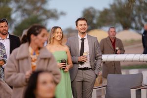 Wedding guests mingling outdoors during a cocktail hour at sunset.