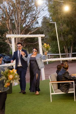 Wedding party poses for creative photo series on outdoor swings at sunset.
