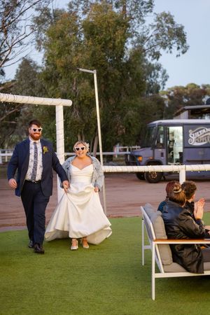 Wedding couple participates in fun outdoor photo session with unique swinging poses on a grassy lawn.