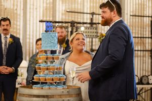 Wedding reception setup in a rustic venue with blue tiered cake and guests celebrating.