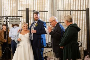 Wedding ceremony guests gather in an elegant venue with vertical wood paneling and natural light.