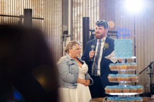Event guests mingle and celebrate in a rustic wood-paneled venue with decorative lighting.