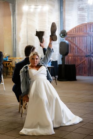 Wedding celebration features playful indoor dance moves in rustic venue setting.