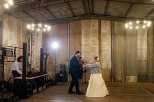 Panoramic view of an industrial-style wedding venue with corrugated metal walls and string lighting.