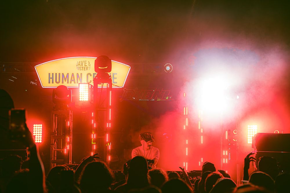 Live music performance with dramatic red stage lighting and silhouetted crowd in foreground.
