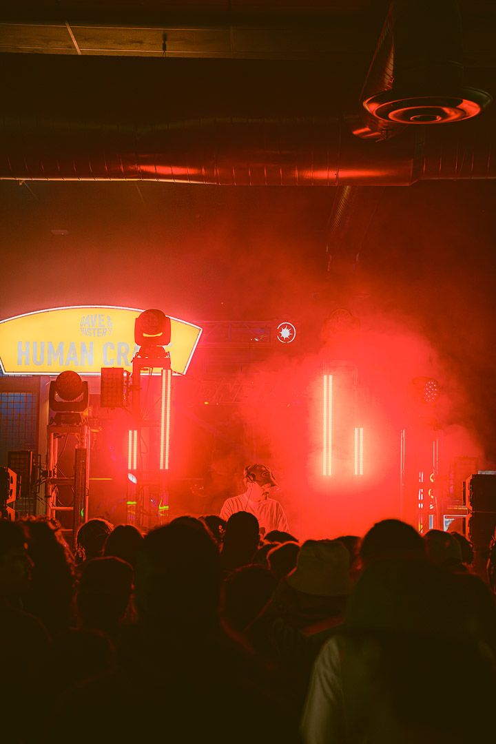 Concert crowd silhouettes against dramatic red stage lighting during a nighttime performance.