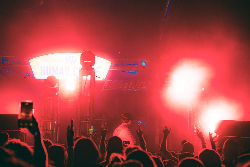 Silhouettes of concert audience against vibrant red stage lighting creating a dramatic atmosphere.