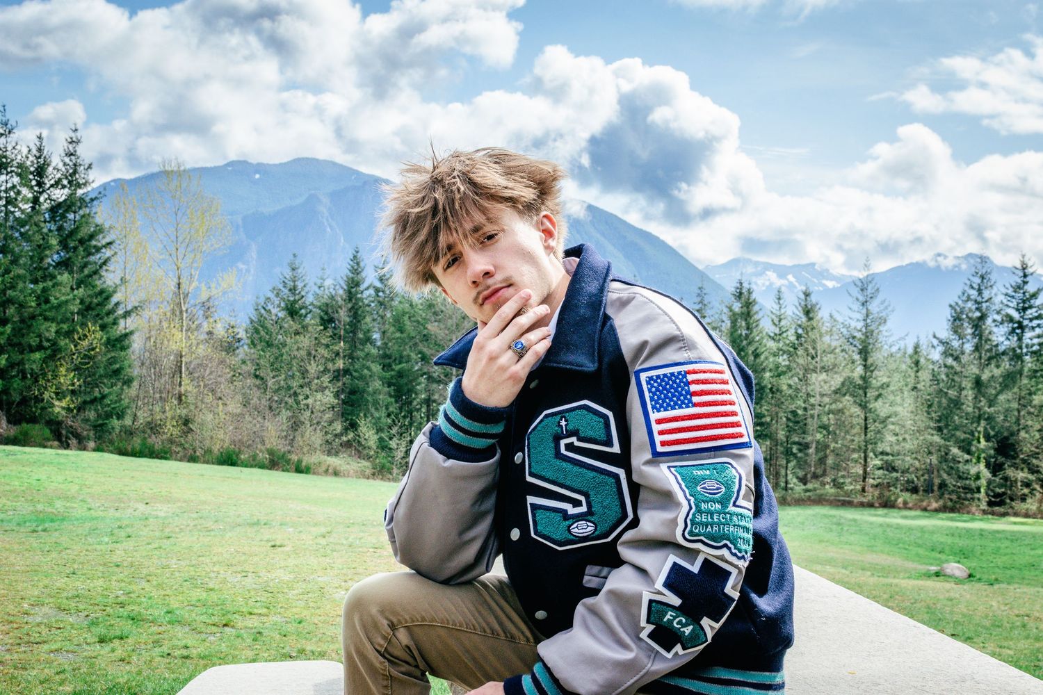 High school Seattle senior wearing a varsity jacket at Snoqualmie with mountain views in the background.