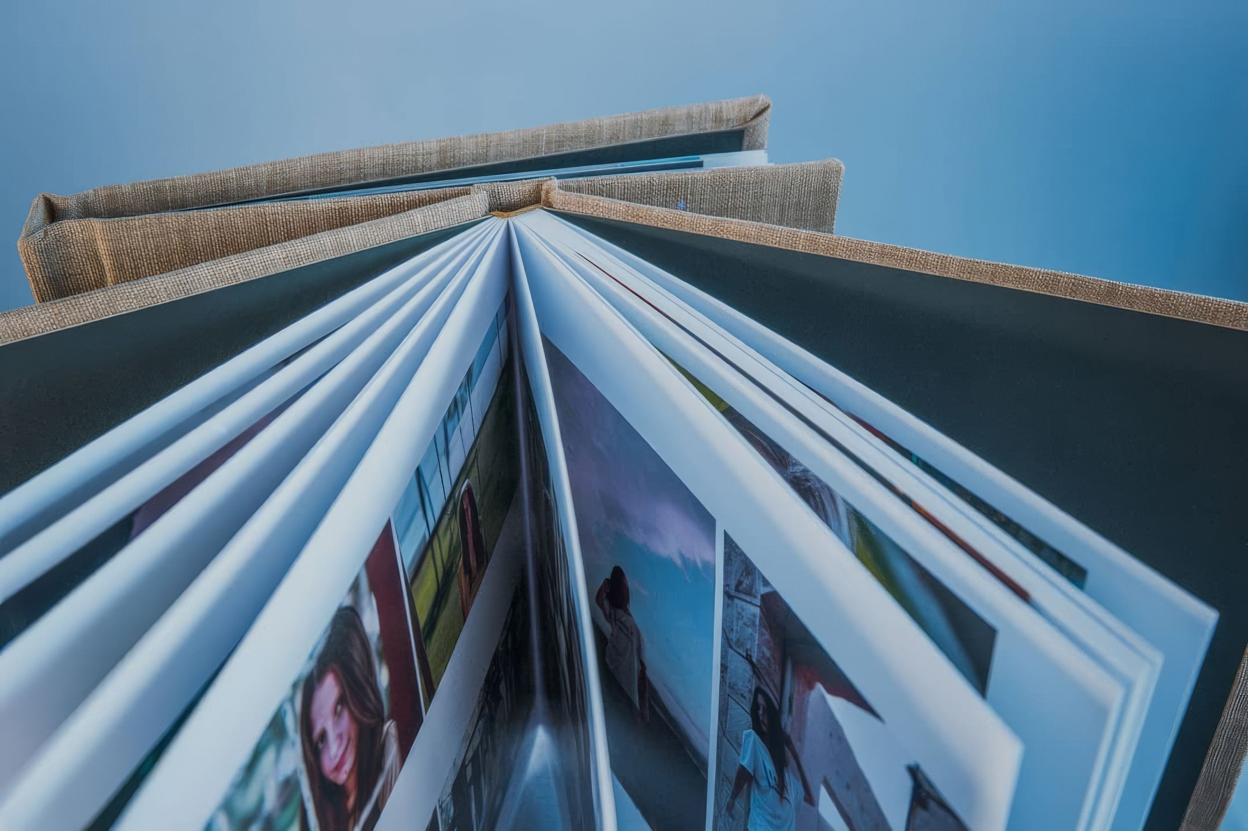 Low angle view of an open photo album with colorful images fanned against a blue sky.  Fotógrafo en Formosa