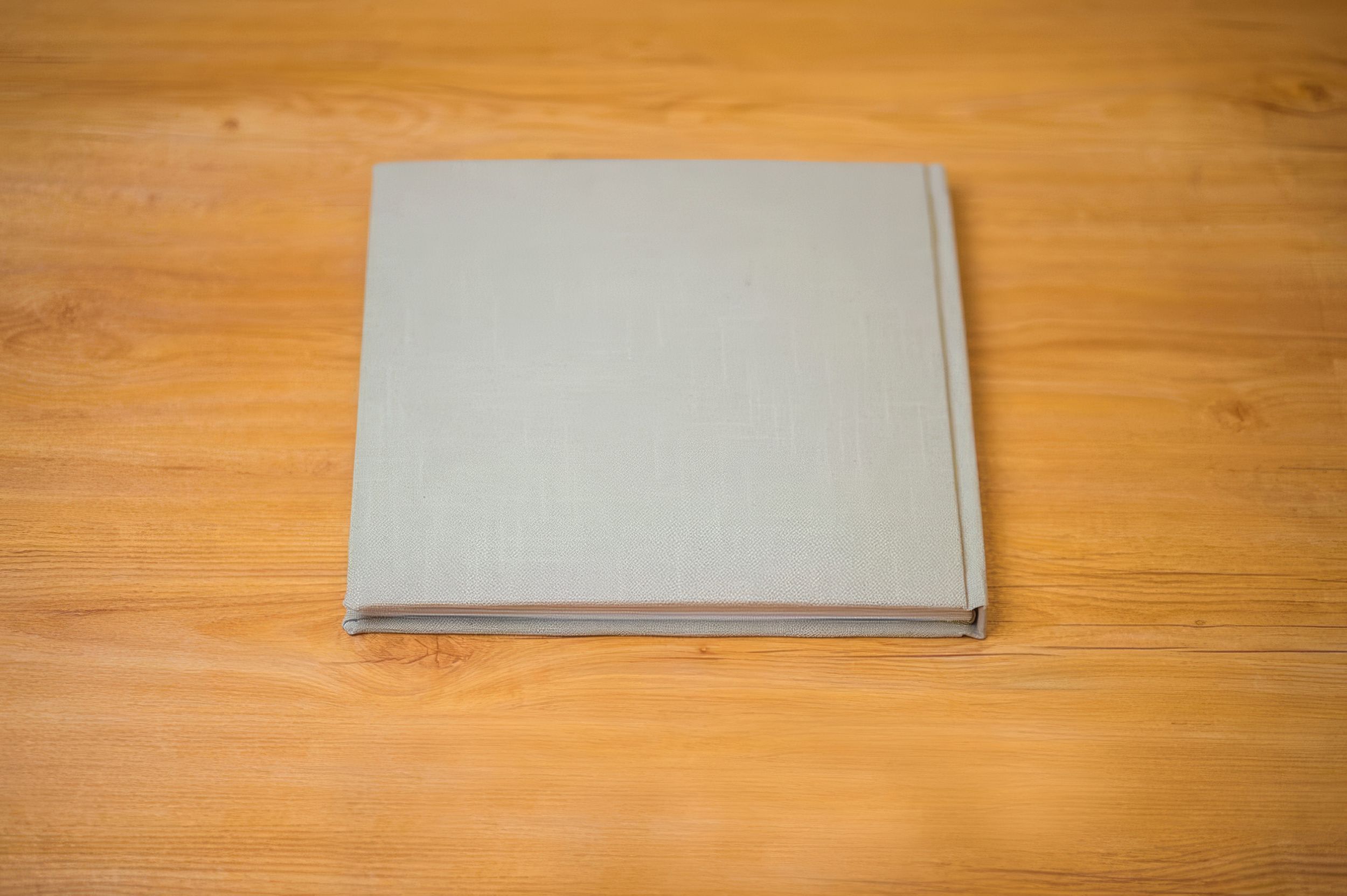 Gray linen hardcover photo album lying flat on a wooden surface.  Fotógrafo en Formosa