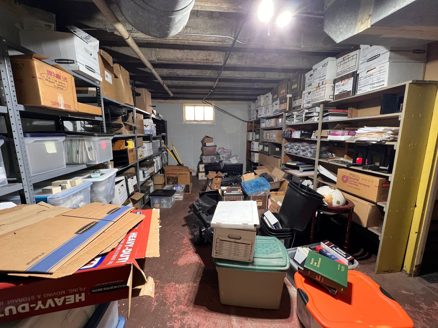 Storage area with exposed ceiling beams and various boxes and equipment scattered throughout the space.