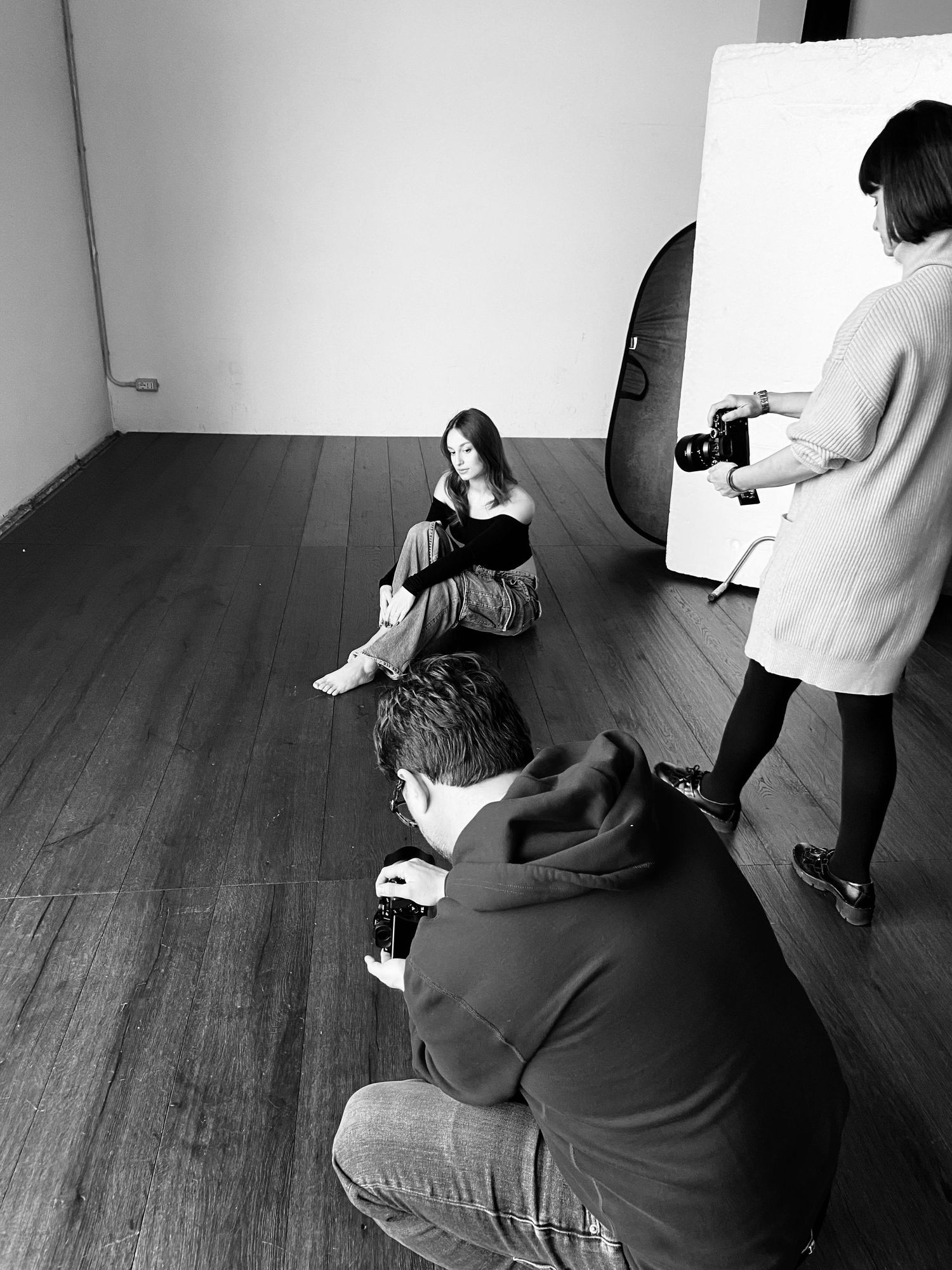 Behind the scenes photo shoot showing photographer and subject in studio setting.
