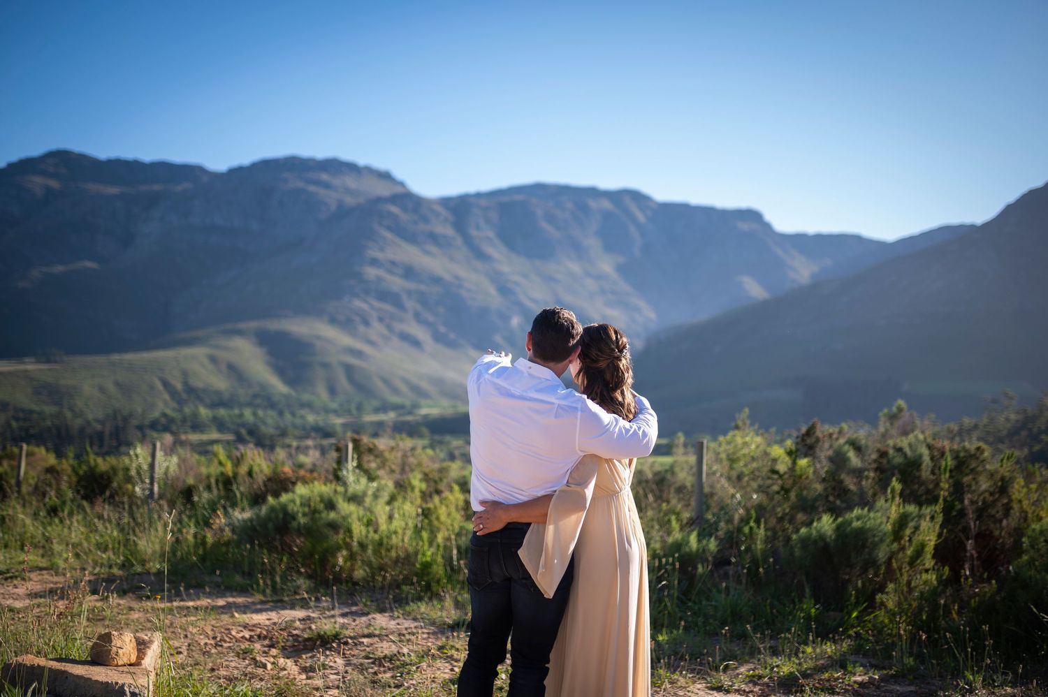 Scenic mountain landscape in Franschhoek wine region with vineyards and distant peaks in golden sunlight.
