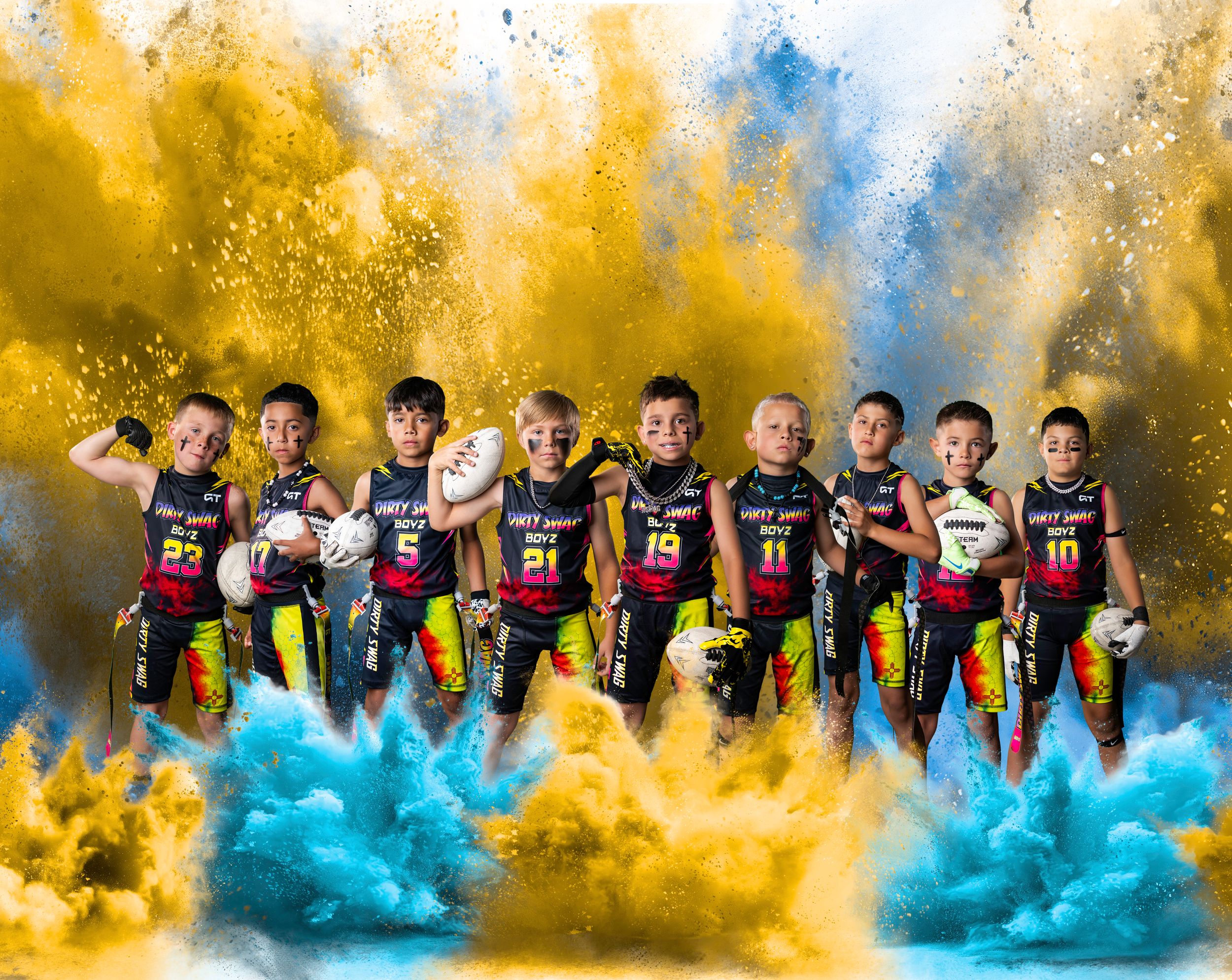 Youth football team poses dramatically with blue and yellow powder explosions in a professional sports portrait.