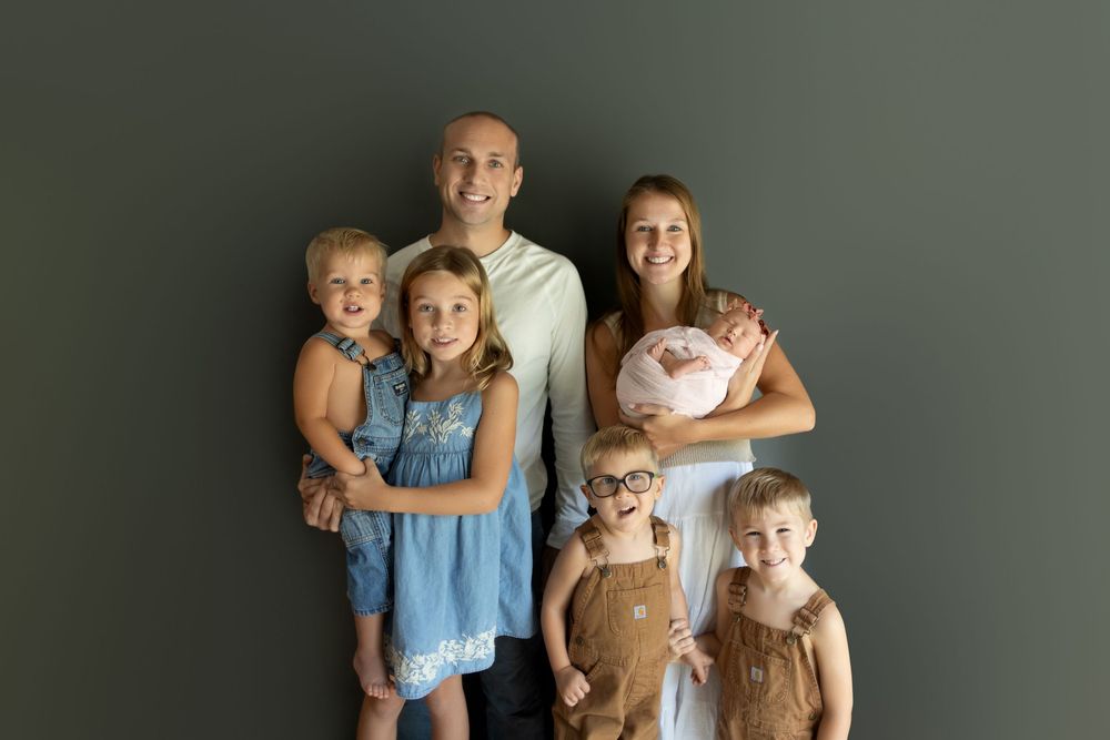 A family wearing coordinated blue and neutral tones poses together for a casual portrait session.