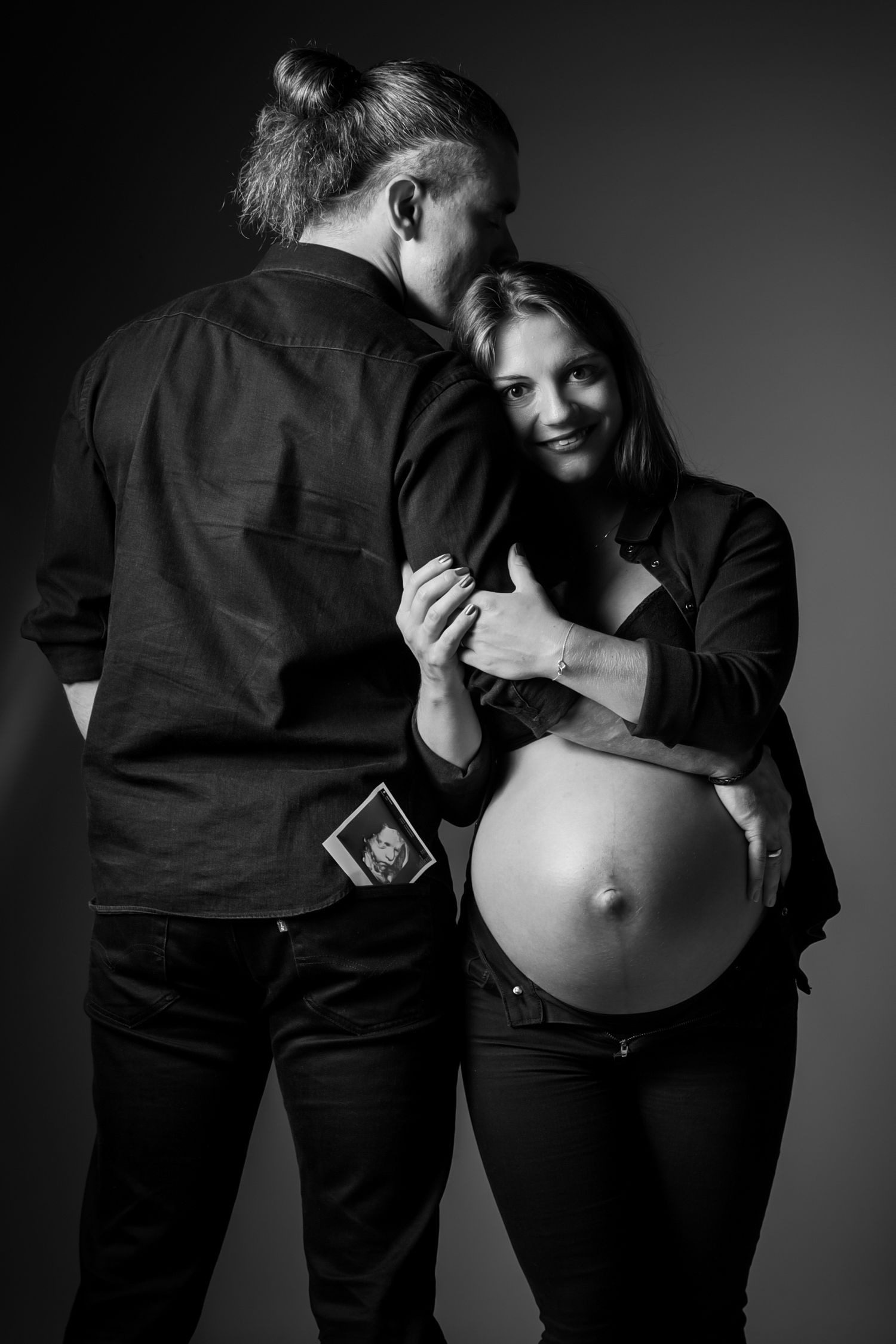 Schwangerschaftsfoto im Fotostudio in Gelsenkirchen-Hassel-.Paar im innigen Moment, er hat sie im Arm, sie kuschelt sich liebevoll an.
