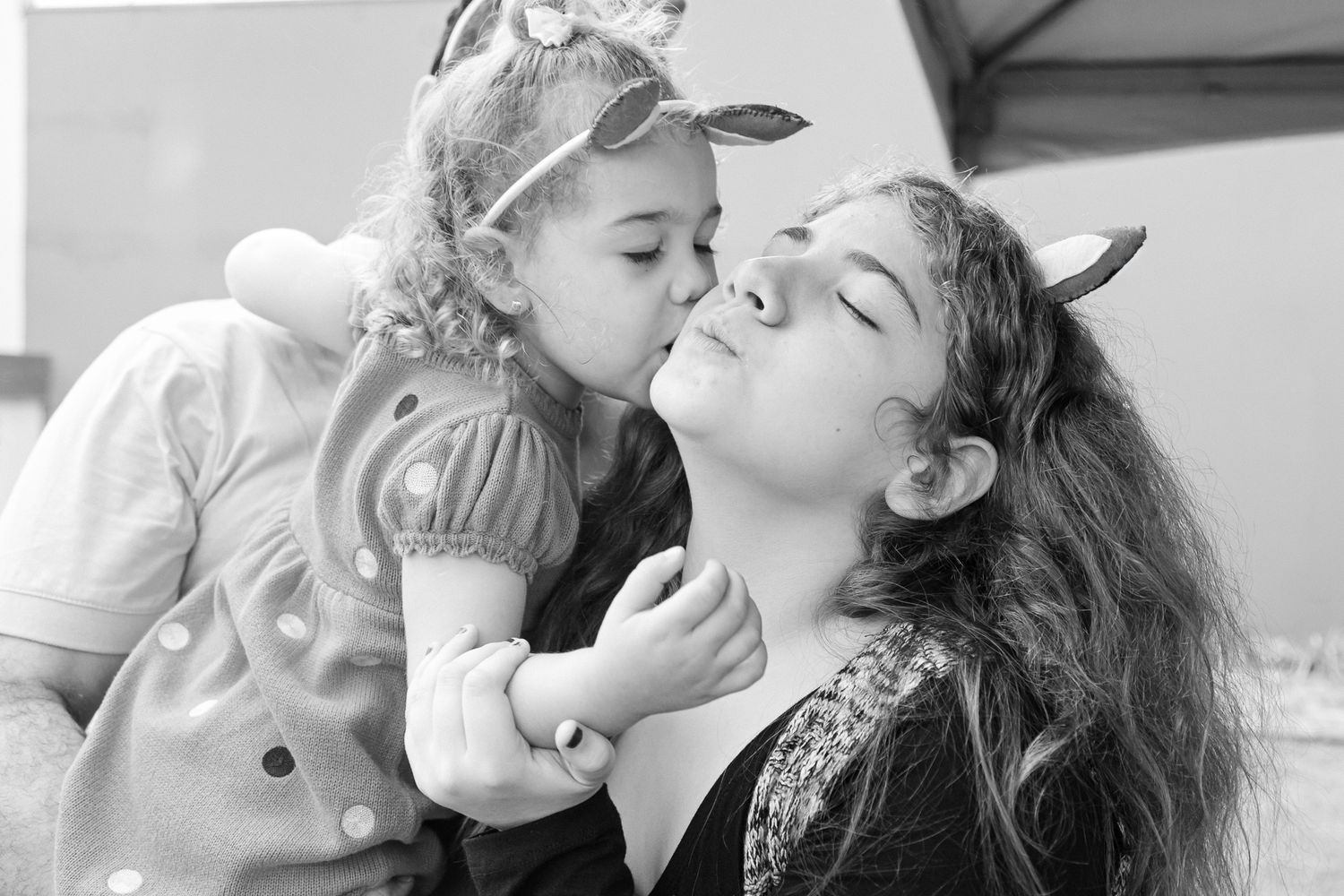 A collection of five black and white photographs showing affectionate family moments and tender kisses.