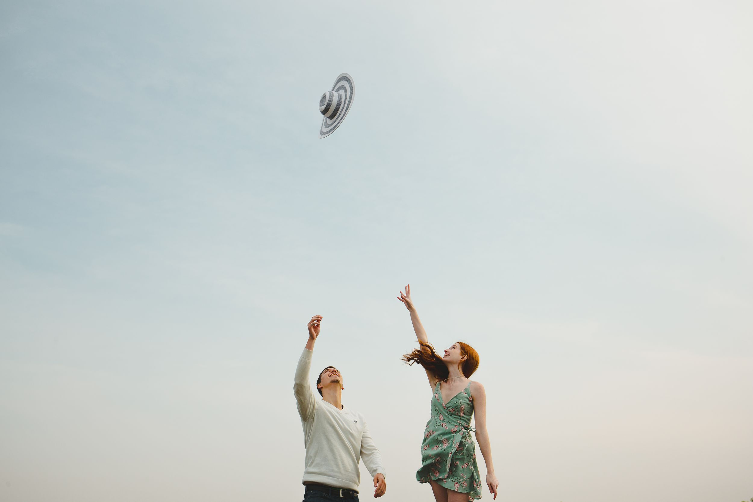 Two people stand together against a bright sky with their arms raised in a celebratory pose.