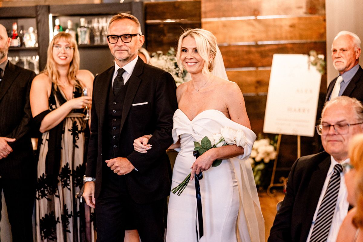 Bride and groom walking hand in hand near lakefront venue in Ontario