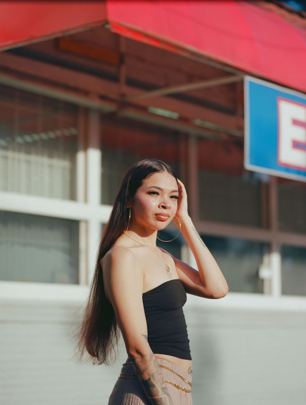 Athletic young woman in black crop top poses confidently against urban background in series of dynamic photos.