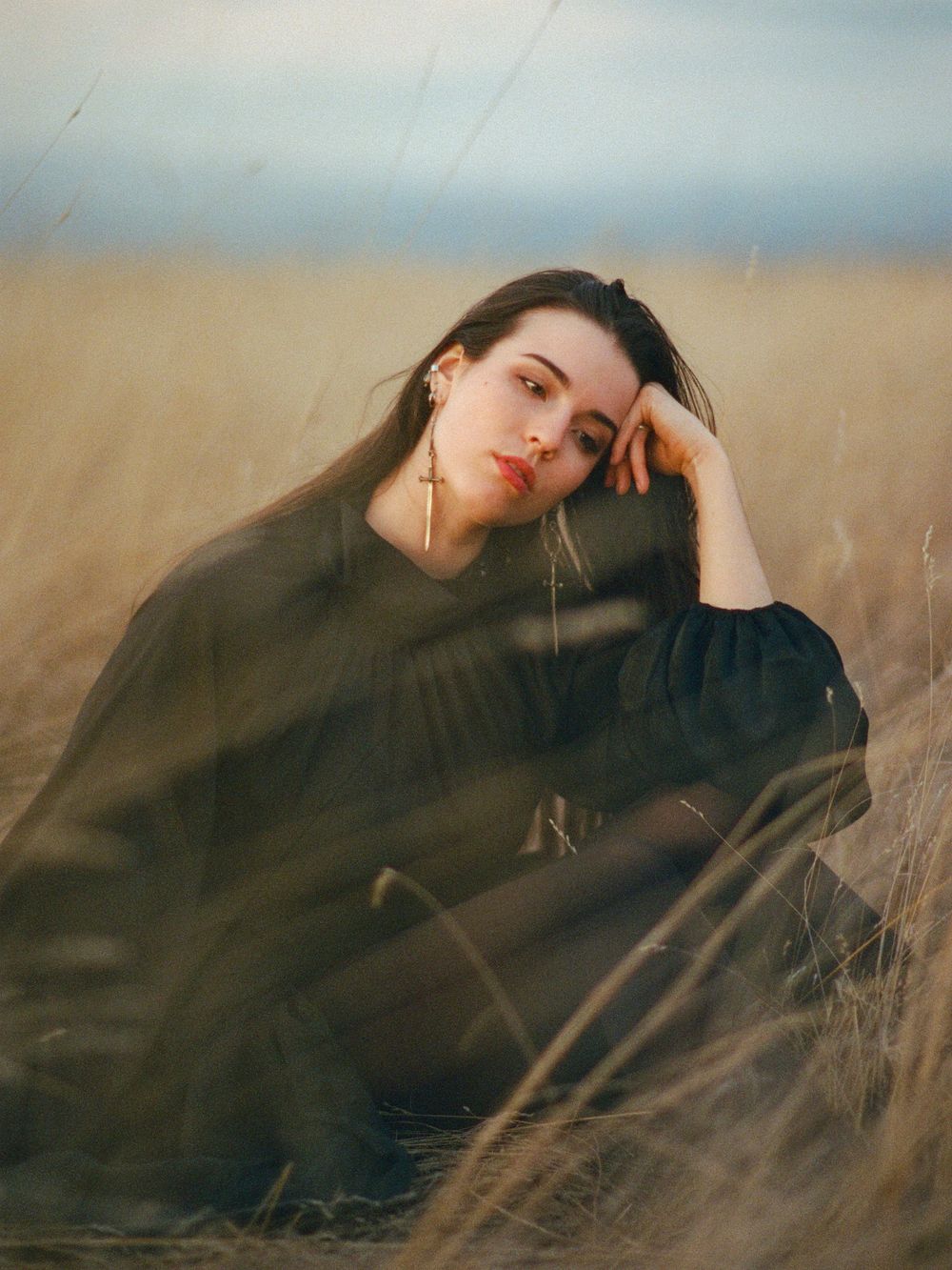 A series of dreamy portraits showing a figure in black against a blurred golden field of wheat at sunset.