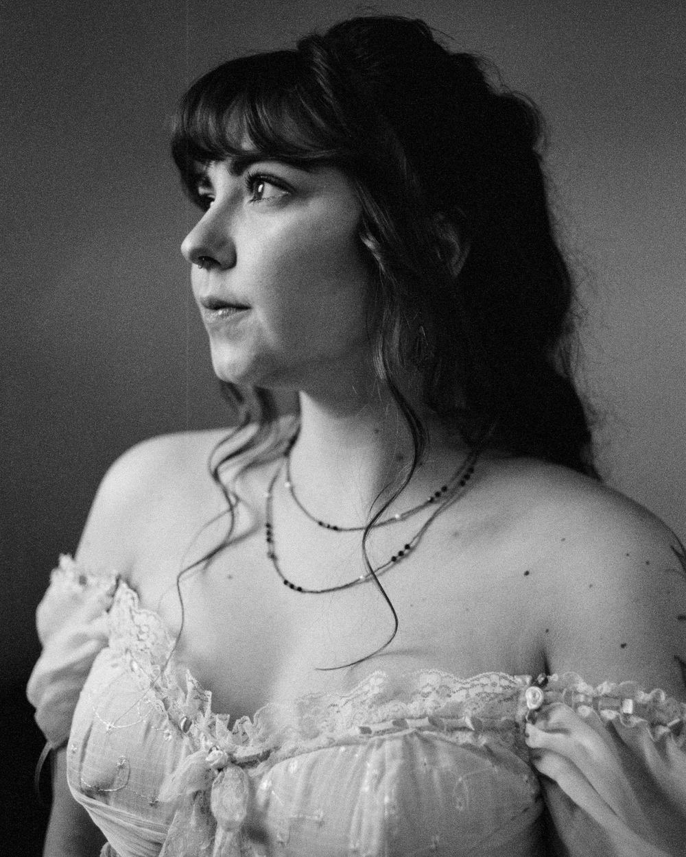 A monochromatic portrait series showing someone in a delicate off-shoulder dress with ruffled details.