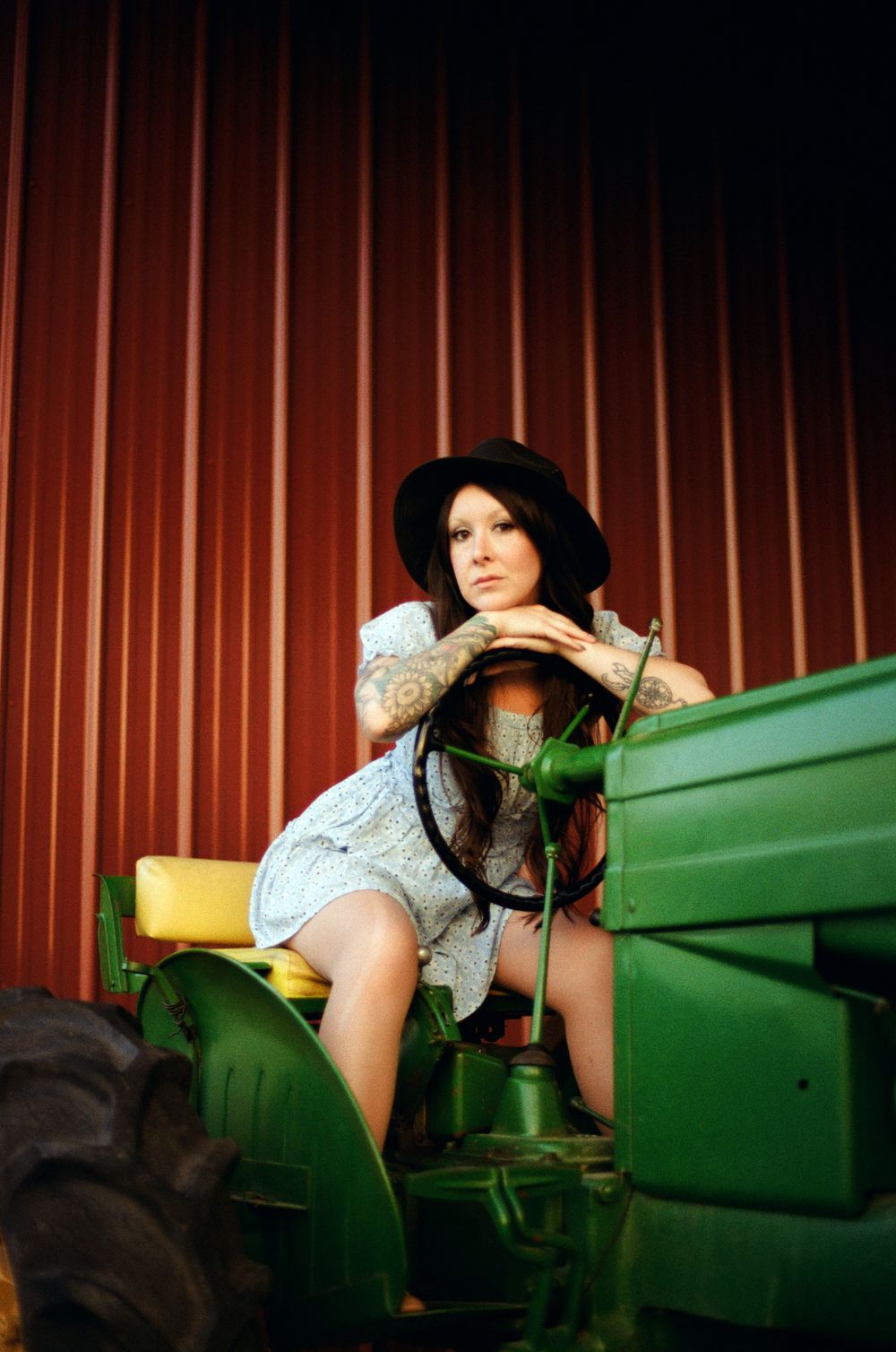 A woman in a polka dot dress poses on green stadium bleachers in a retro-style photoshoot.