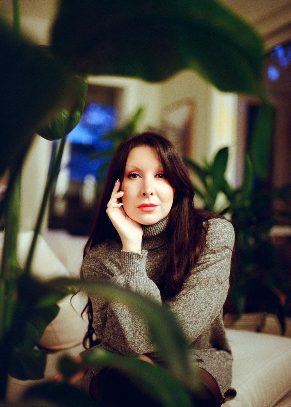 Portrait series showing a figure in a grey sweater photographed in low light with plant shadows and mood lighting.