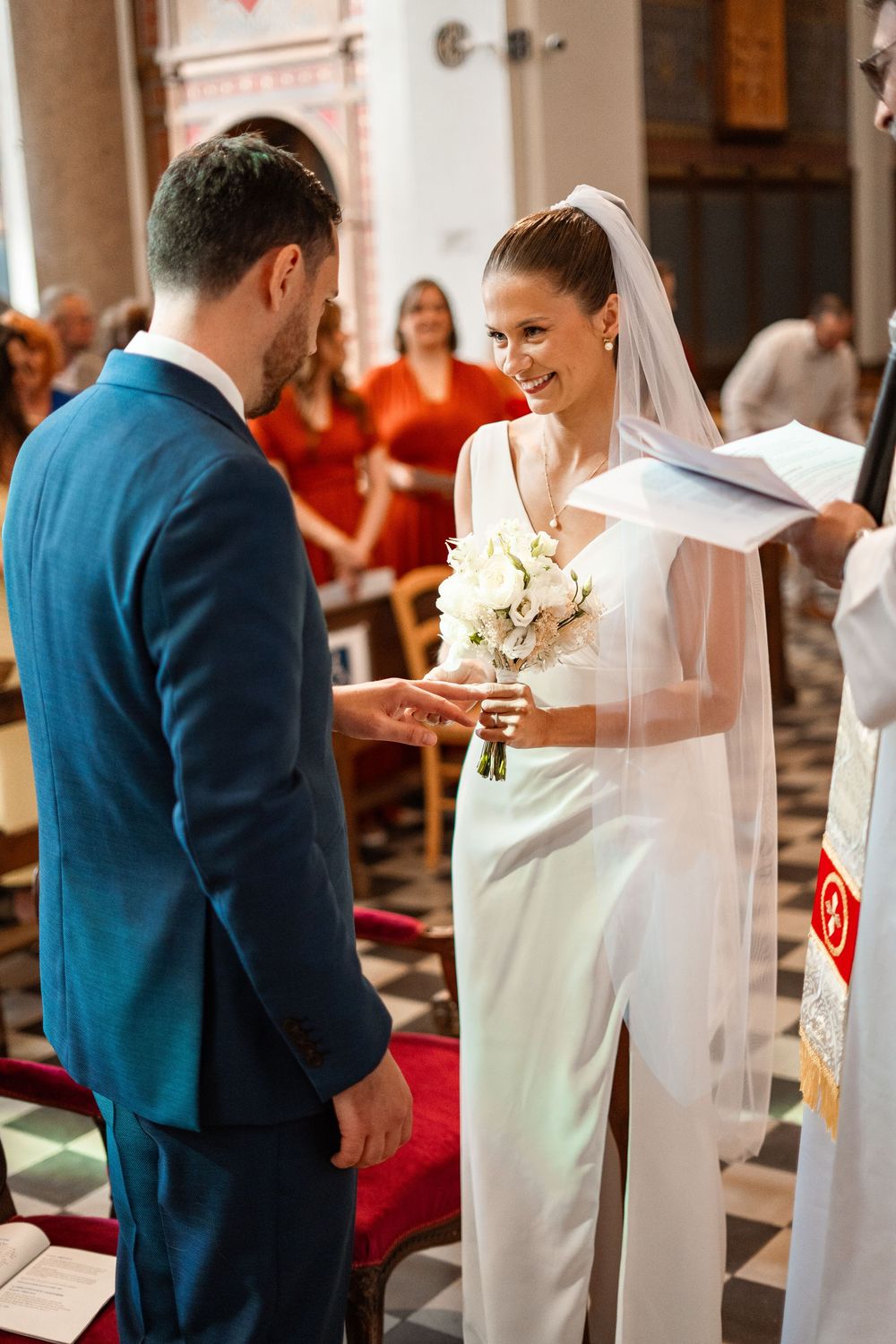 Couple exchanging vows during a traditional church wedding ceremony with guests looking on.
