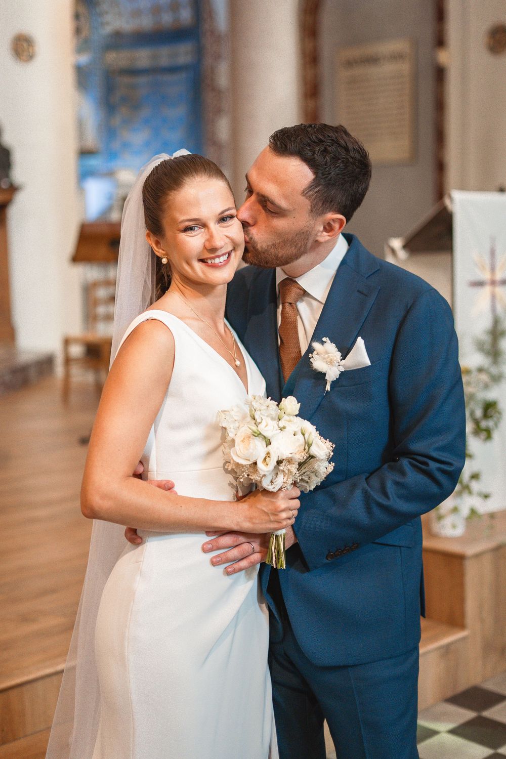A couple shares intimate moments while holding a white bouquet during their wedding celebration.