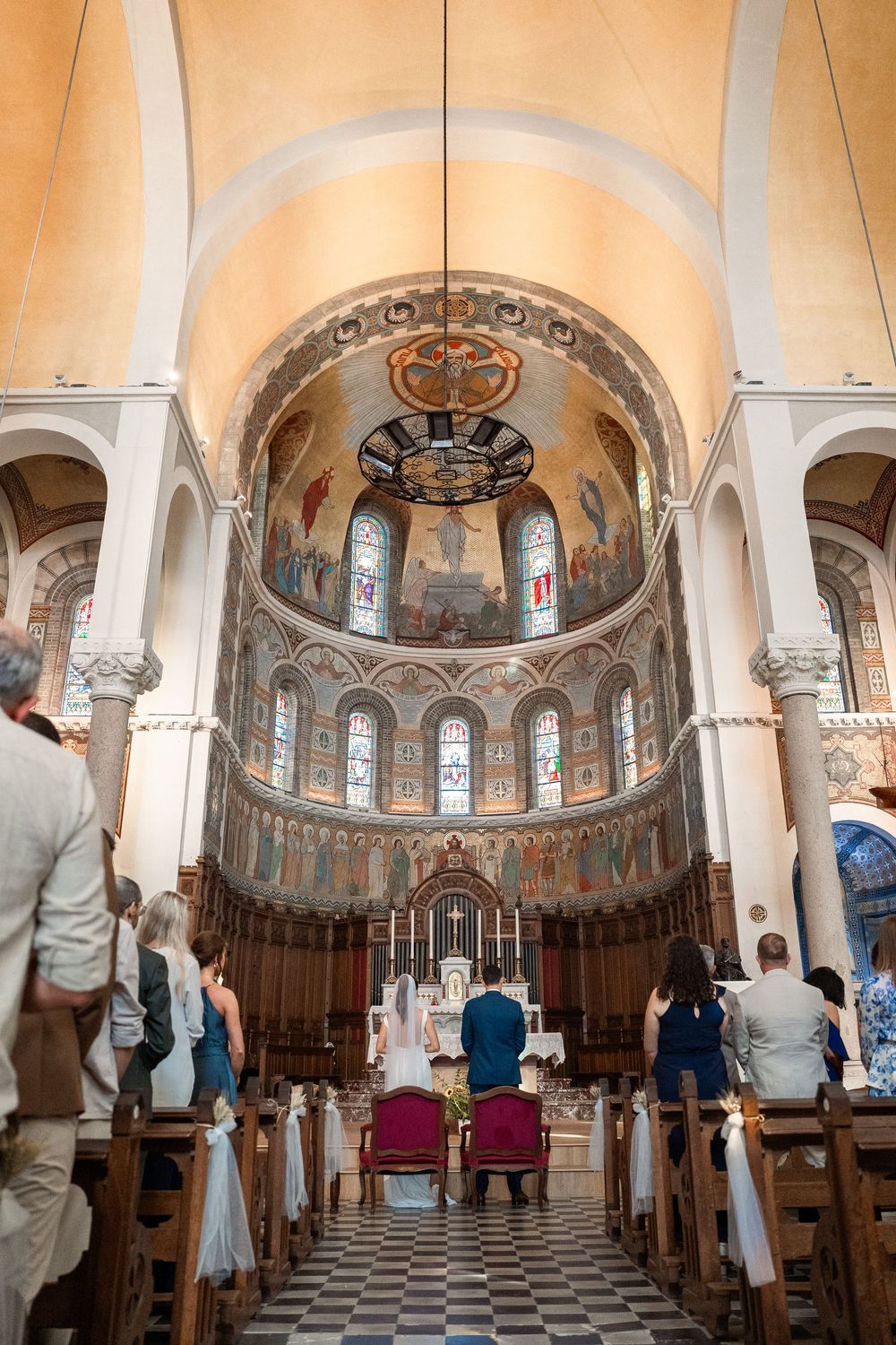 Interior of ornate church sanctuary with arched ceilings, stained glass windows and decorative architectural details.